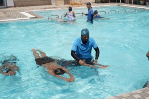 Adult beginner practicing floating with a swim instructor in a clear indoor pool.